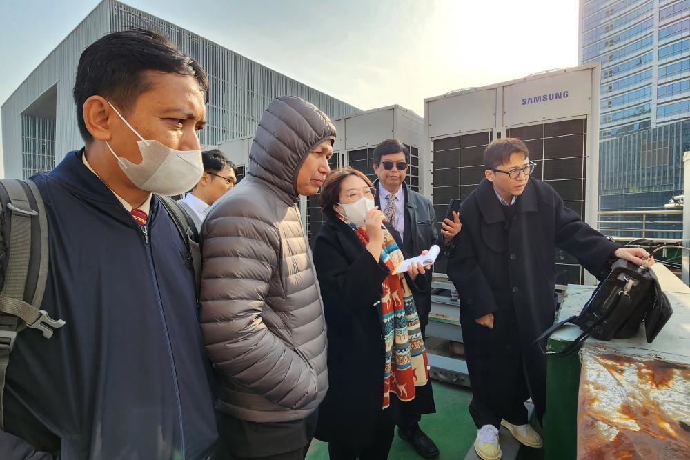 Delegasi Ditjen SDPPI ke rooftop gedung komersial Yongsang Biznet melihat demonstrasi cara pengukuran EMF pada lokasi antena BTS layanan seluler.